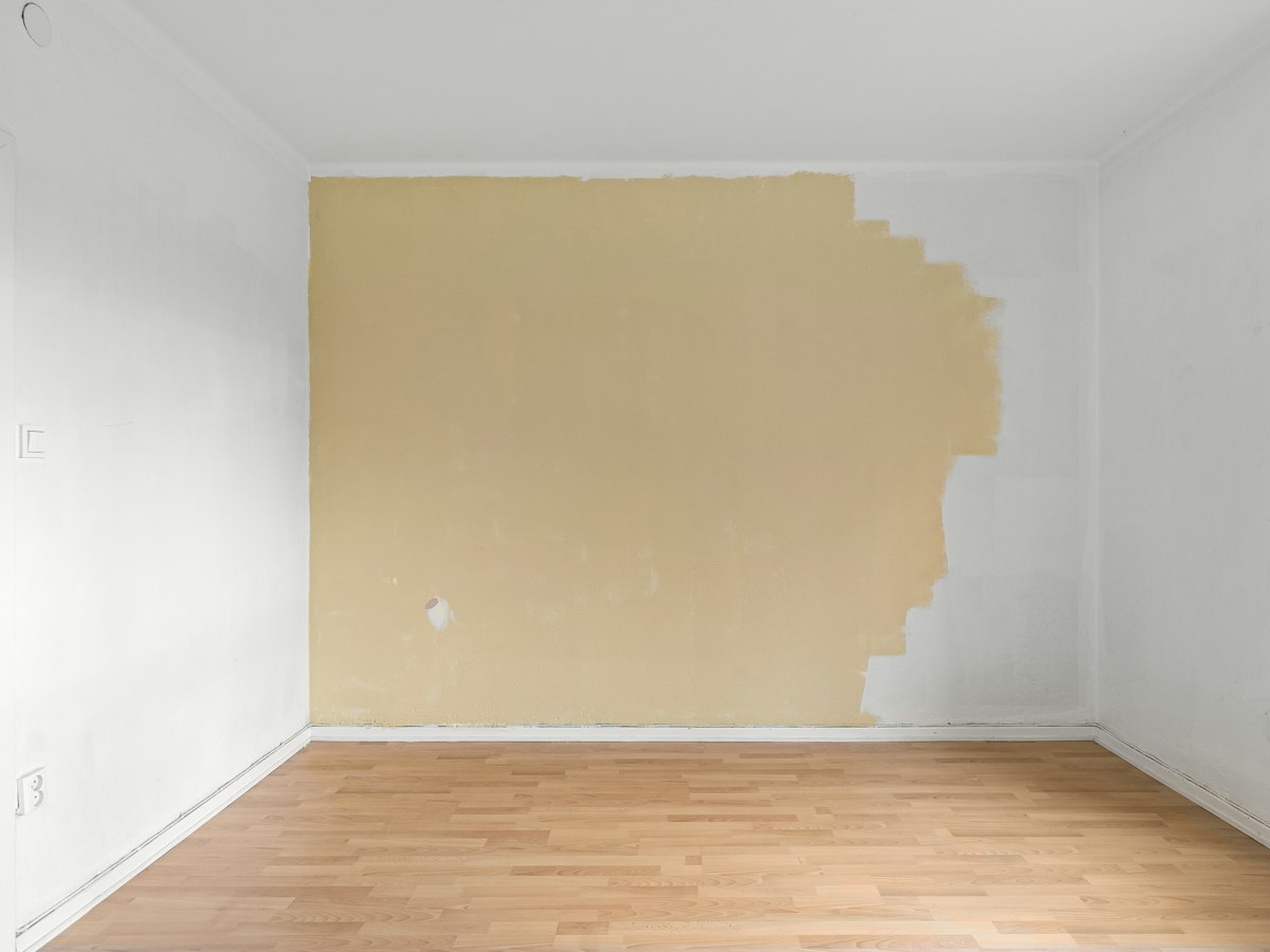 Lyst rom under oppussing med halvmalt vegg